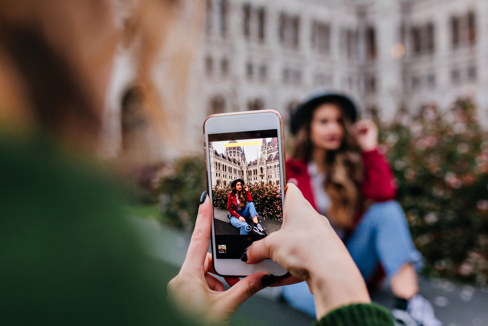 Девушка фотографирует подругу на телефон